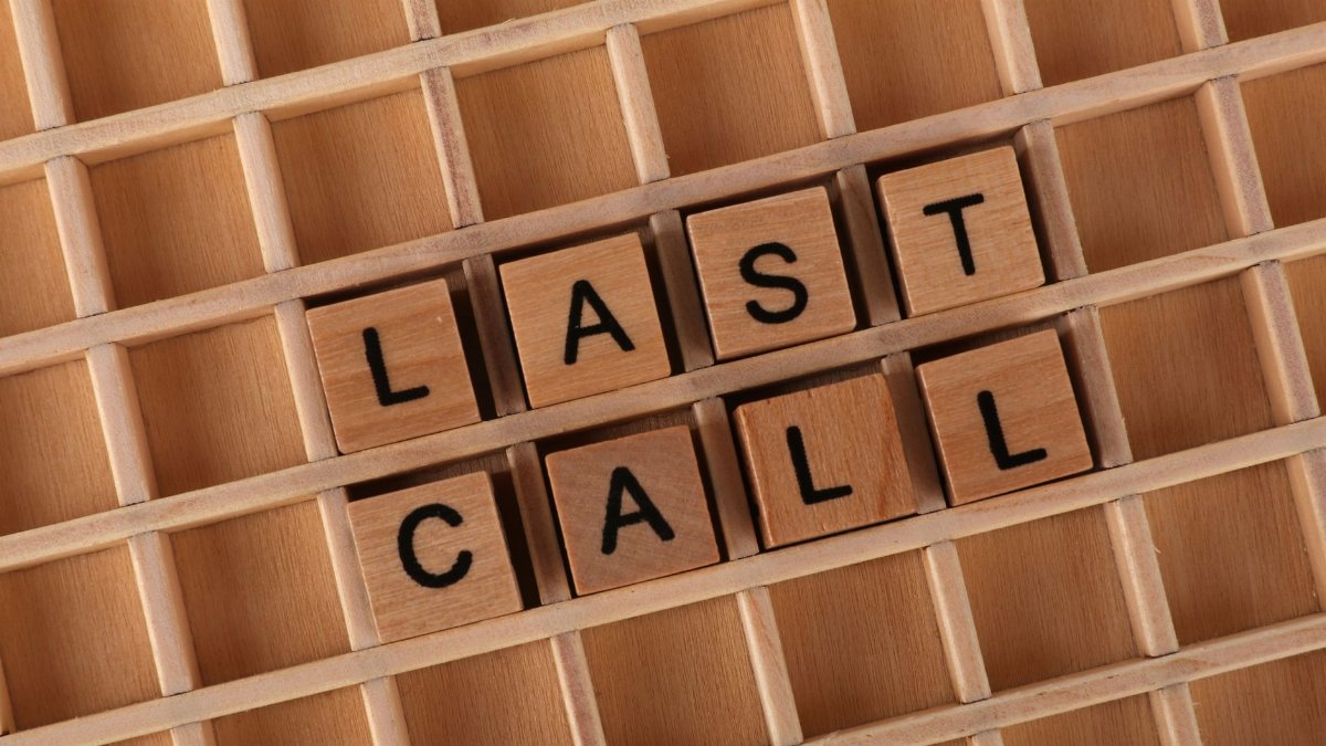 Wooden Scrabble tiles spelling 'Last Call' on a wooden grid background.