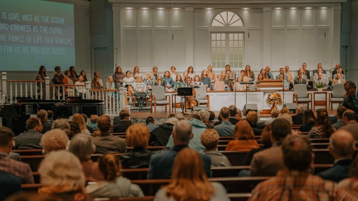 A large congregation seated in a church auditorium during a service with choir and musical instruments.
