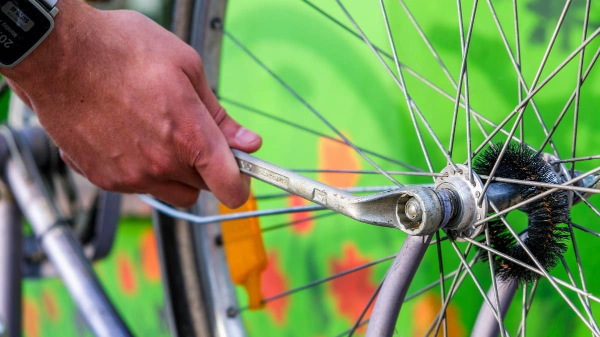 Close-up of a man repairing a bicycle wheel with a wrench. Focus on hand and spokes.