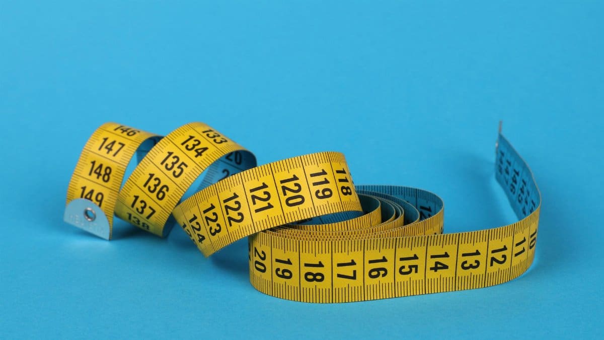 A vibrant close-up of a coiled yellow and blue measuring tape on a blue background.