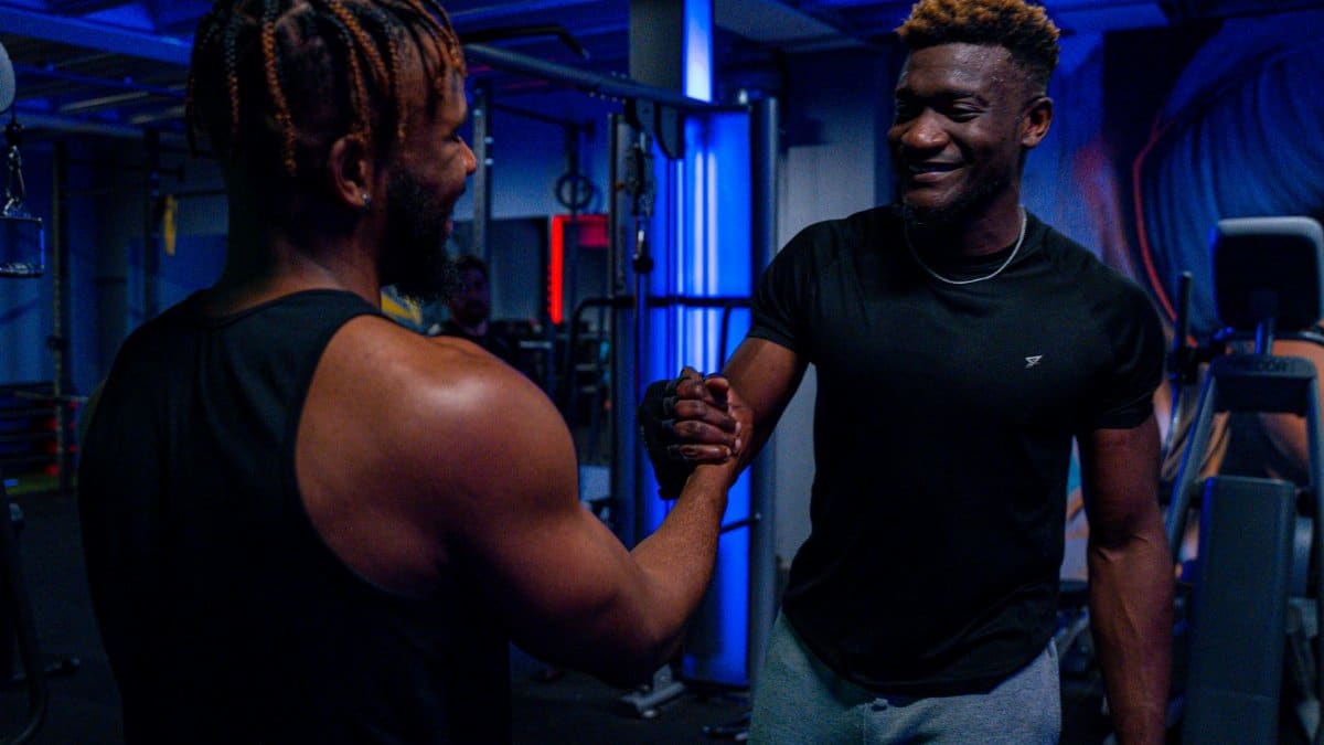 Two men in sportswear shaking hands in a modern gym, promoting friendship and teamwork.