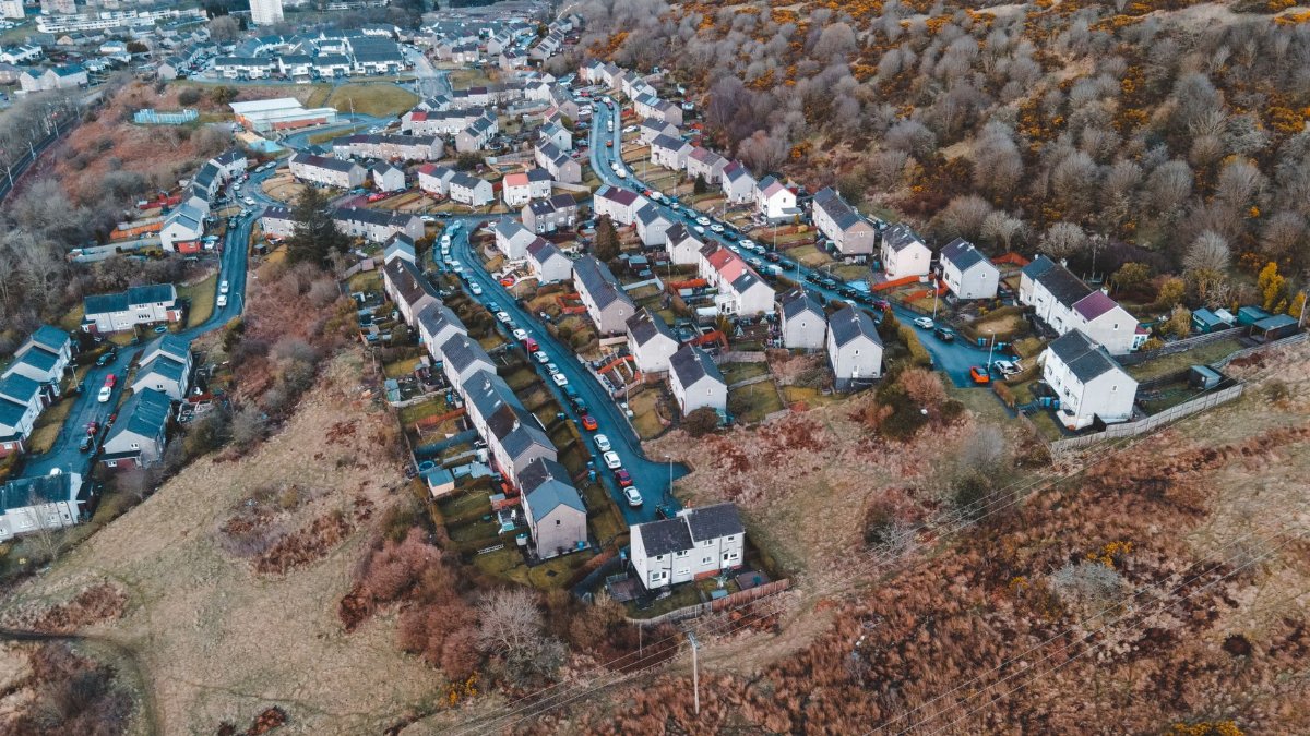 Stunning aerial view of a residential area in Scotland showcasing vibrant autumn colors and hillside homes.