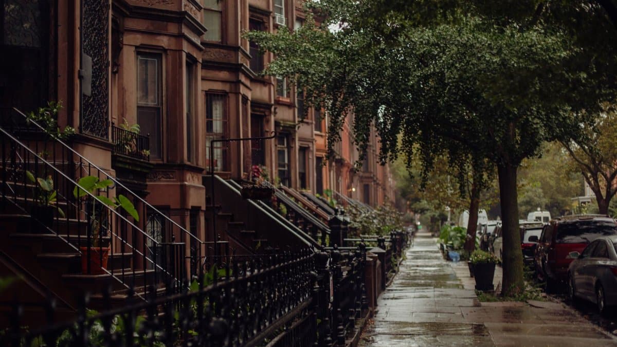 Quaint urban street view of brownstone homes on a rainy New York day.