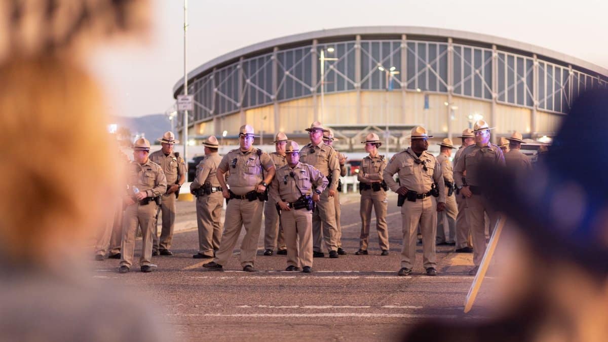 A row of police officers in uniform standing outside a large building during a public event in Arizona.