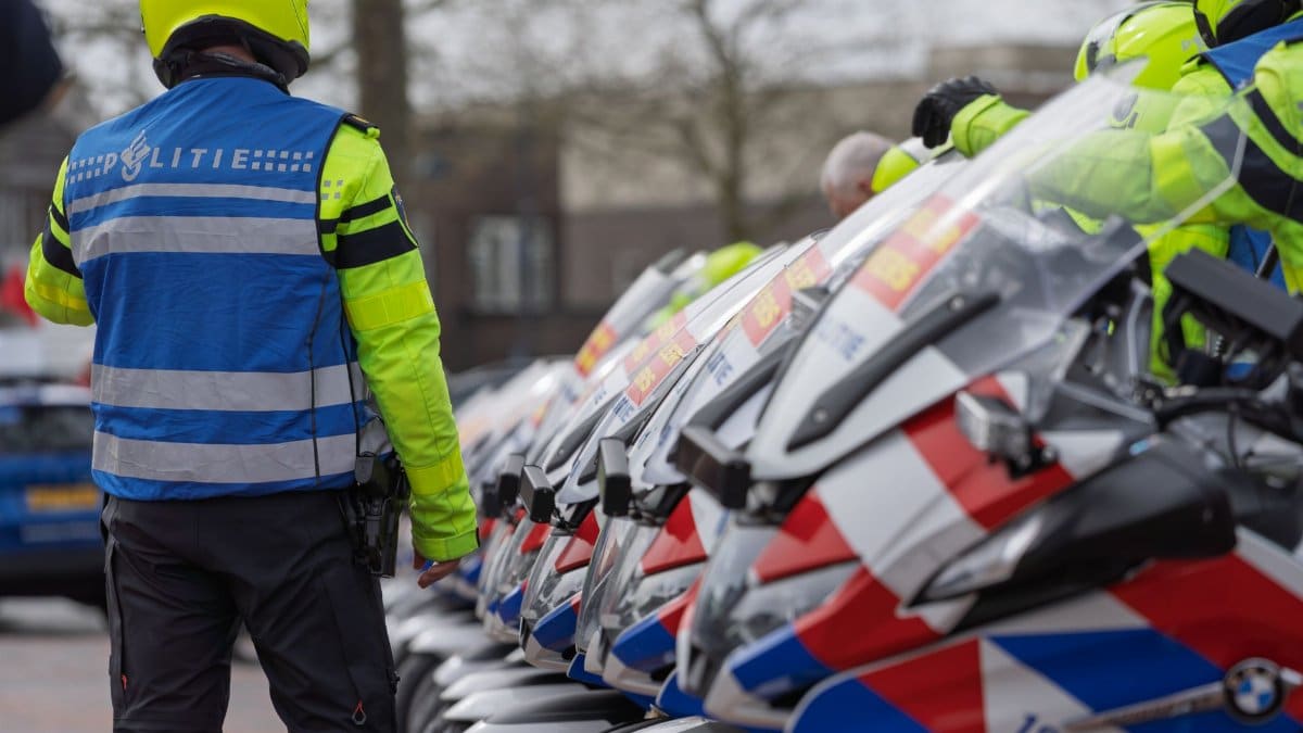 Dutch police officers in reflective gear beside motorcycles, preparing for deployment.