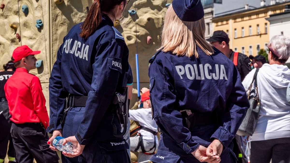 Two police officers in uniform supervise an outdoor climbing activity at a public event.