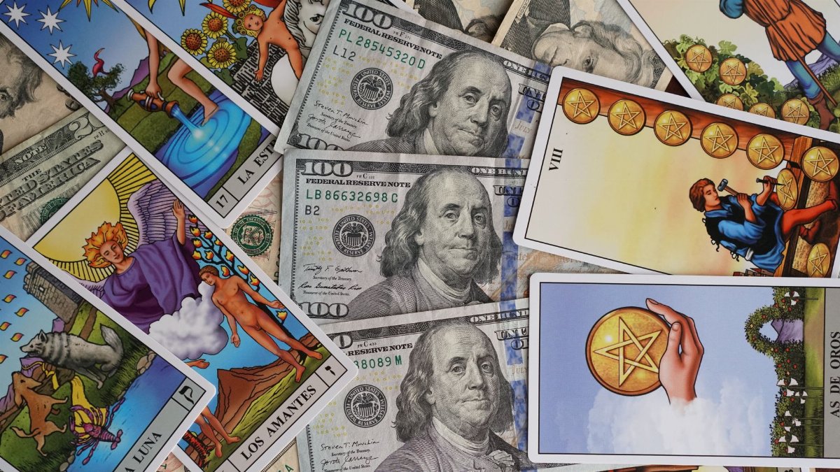 A collection of Tarot cards artfully arranged with US dollar bills, symbolizing fortune and wealth.