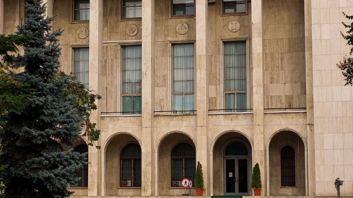 Exterior of a classical building with columns, arches, and greenery, showcasing elegant architecture.