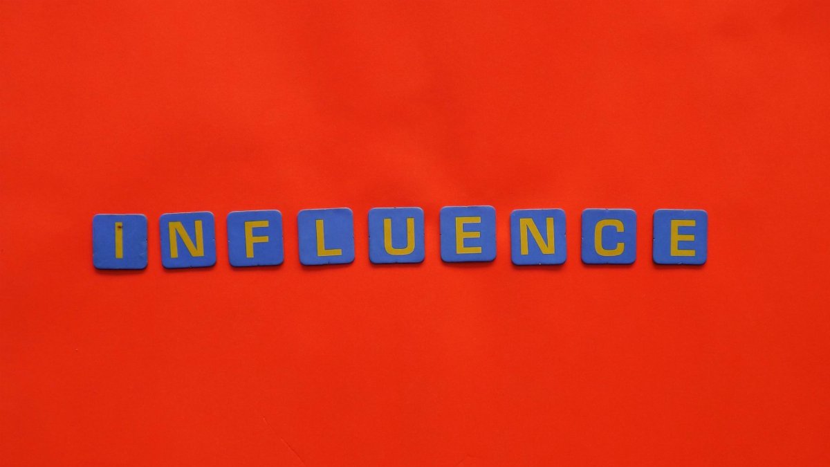 Bold blue letters spelling 'Influence' on a vibrant red background, conveying impact.