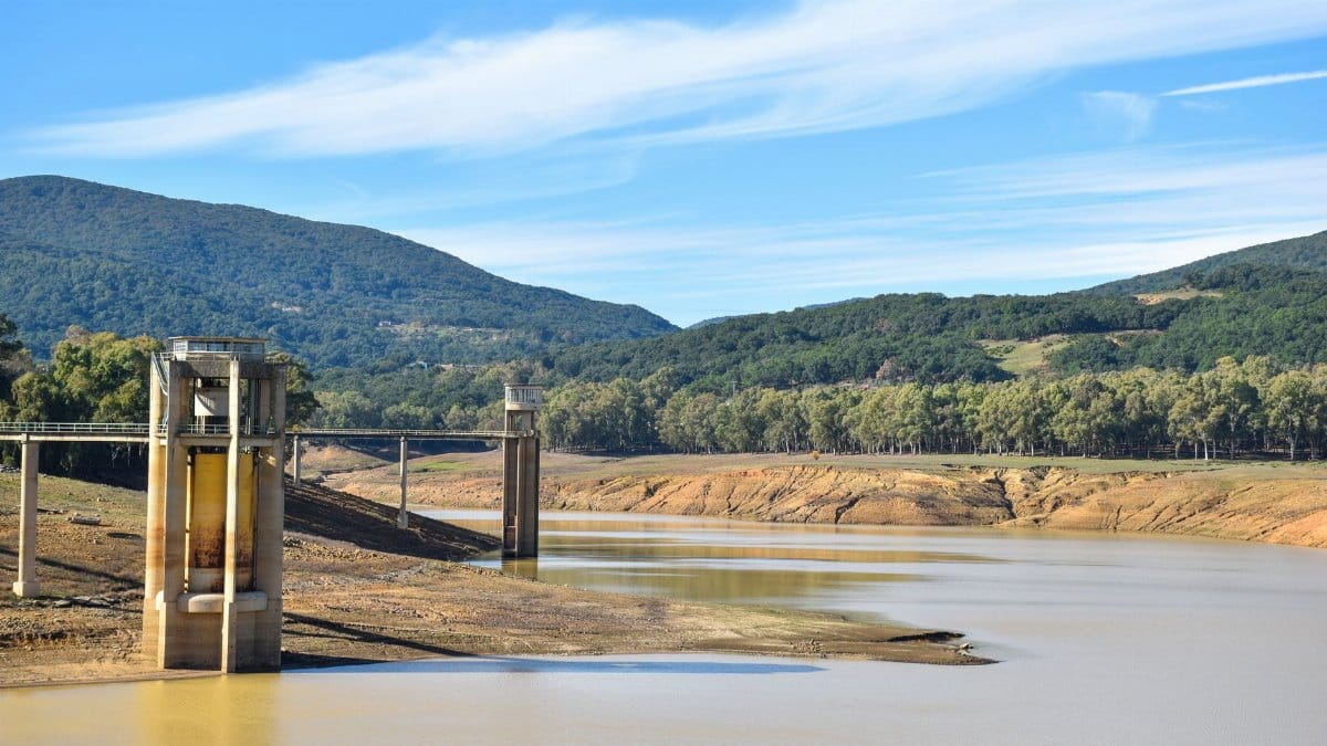 A striking view of a drought-affected reservoir surrounded by mountains and forest.