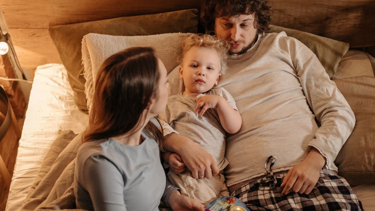 A peaceful family moment with parents and child relaxing in bed, embracing love and togetherness.