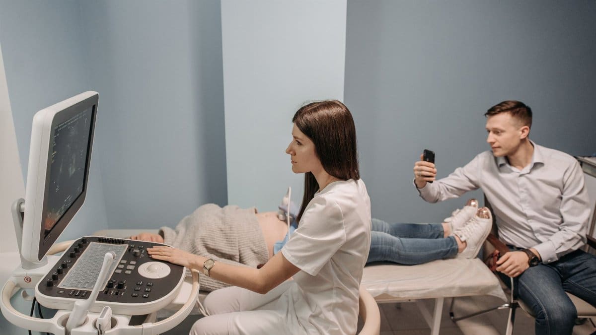 Medical professional conducts ultrasound for expectant couple in clinic.