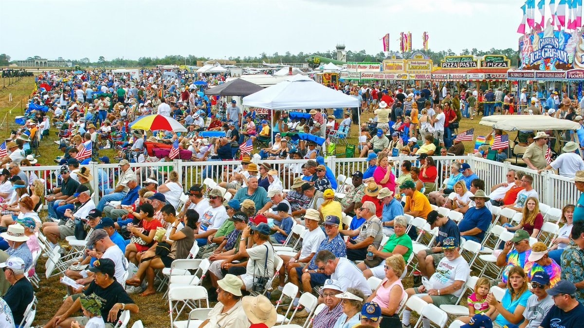 A lively scene of people gathered at an air show in Titusville, Florida, enjoying the festive atmosphere.
