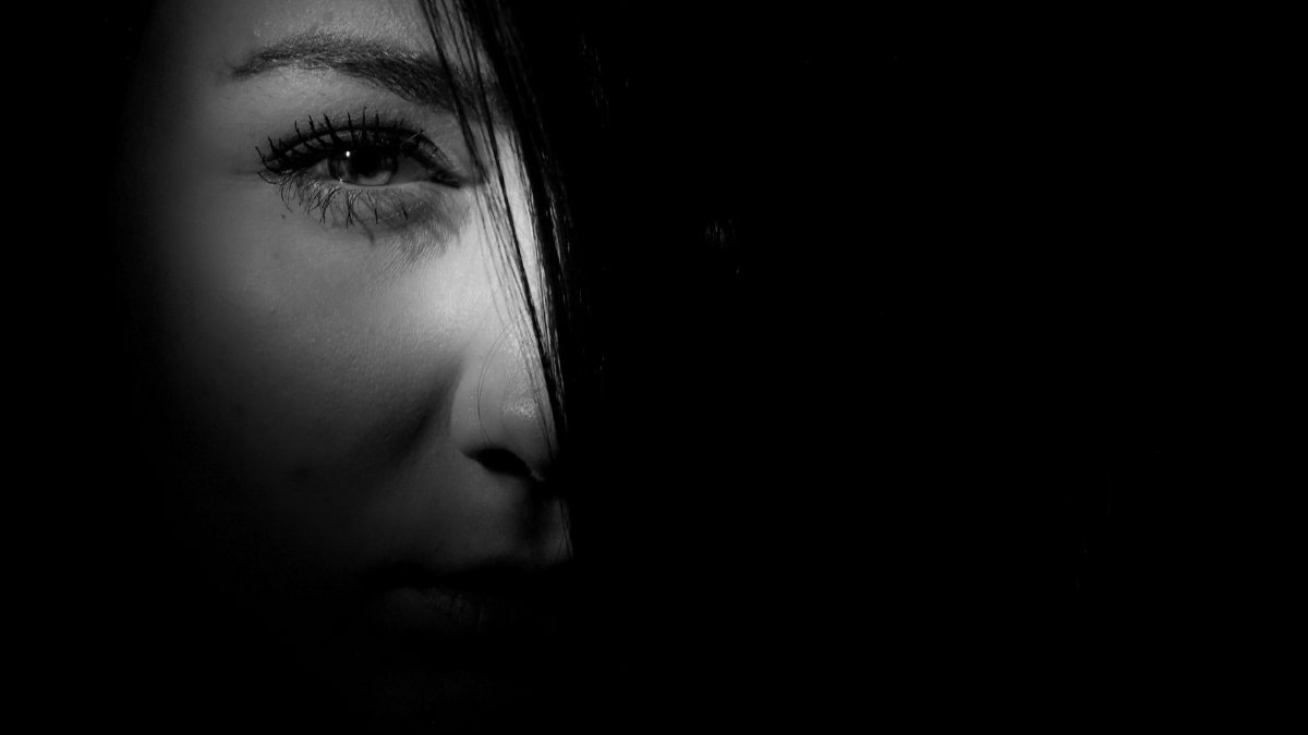 Mysterious black and white portrait of a woman's face in dramatic lighting.