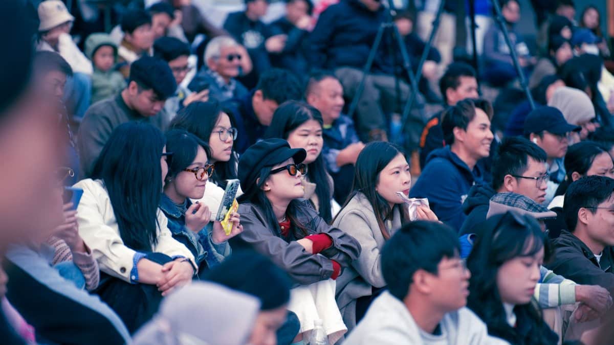 Diverse group of people enjoying a public outdoor event, focused and attentive.