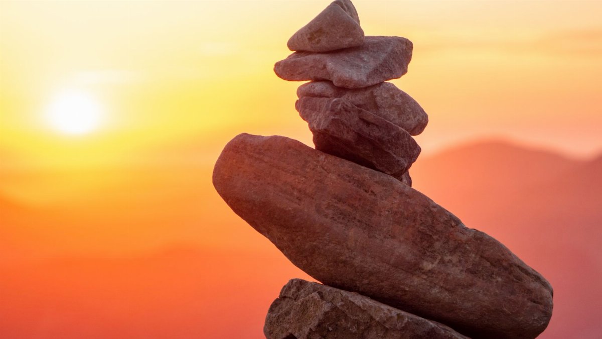 A serene stack of stones silhouetted against a vibrant sunset sky, capturing balance and tranquility.