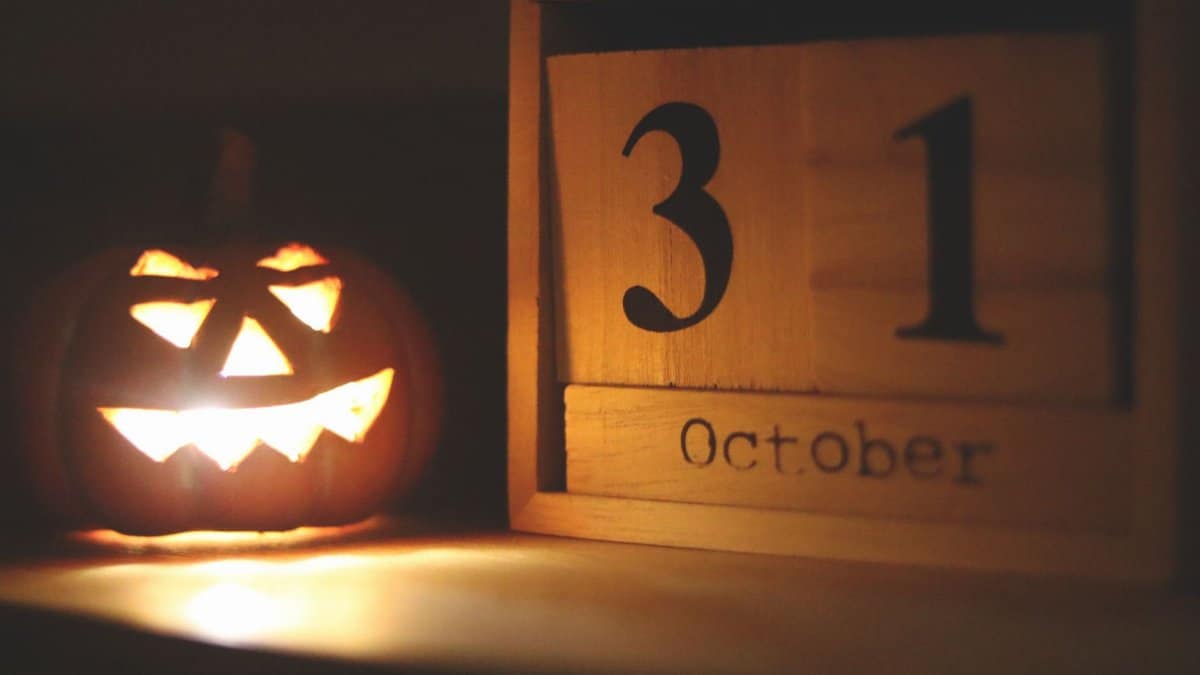 A glowing jack-o-lantern next to a calendar showing October 31, symbolizing Halloween celebration.