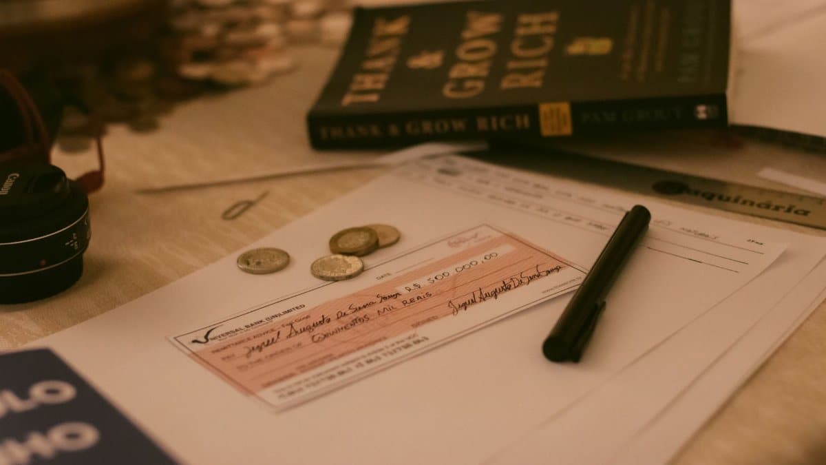 Close-up of a business desk with a check, coins, pen, and financial books, creating a financial planning vibe.