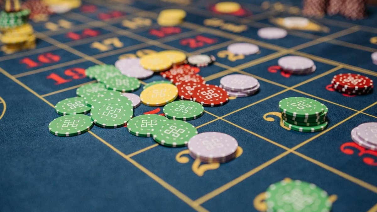 Closeup of colorful casino chips scattered on a roulette table.