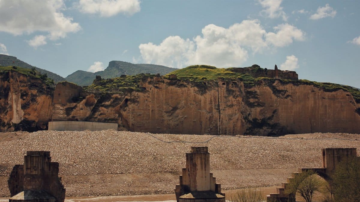 Historic ruins of Hasankeyf Bridge over the Tigris River, dramatic cliffs and landscape in Türkiye.
