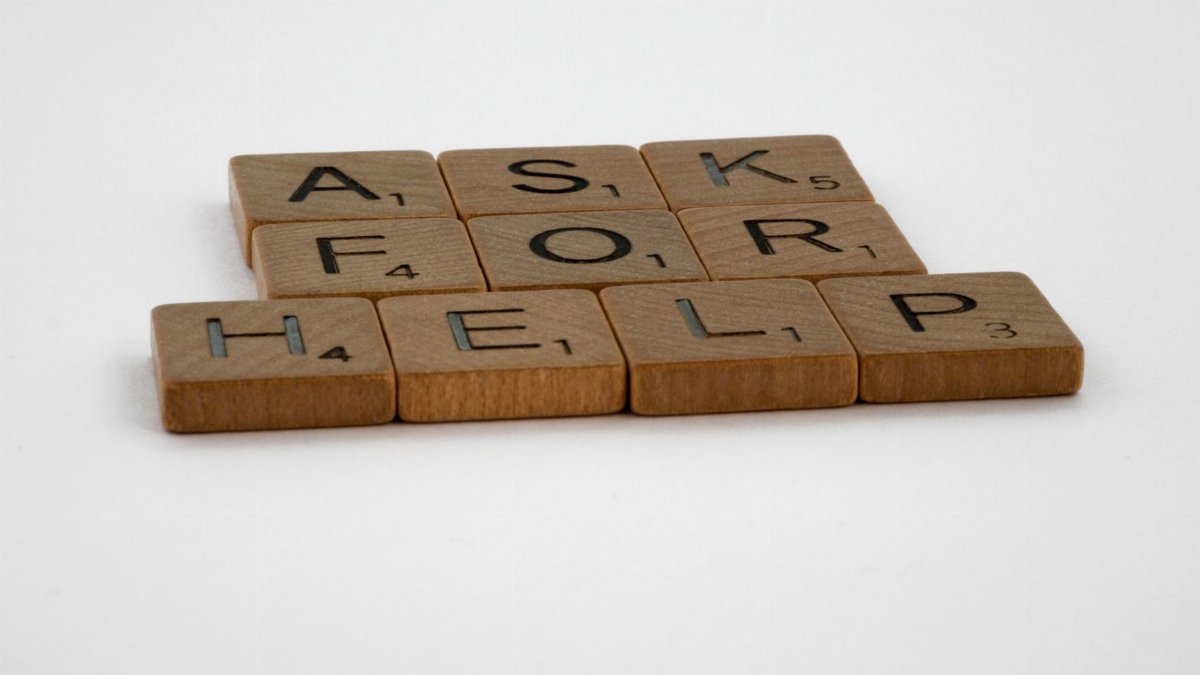 Scrabble tiles arranged on a white background forming the phrase 'Ask for Help', conveying a message of communication.