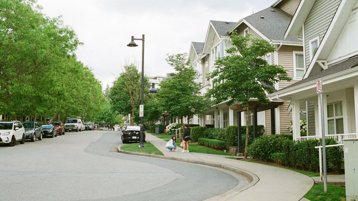 Charming Vancouver street with families enjoying a day outdoors among lined trees and houses. Urban community scene.