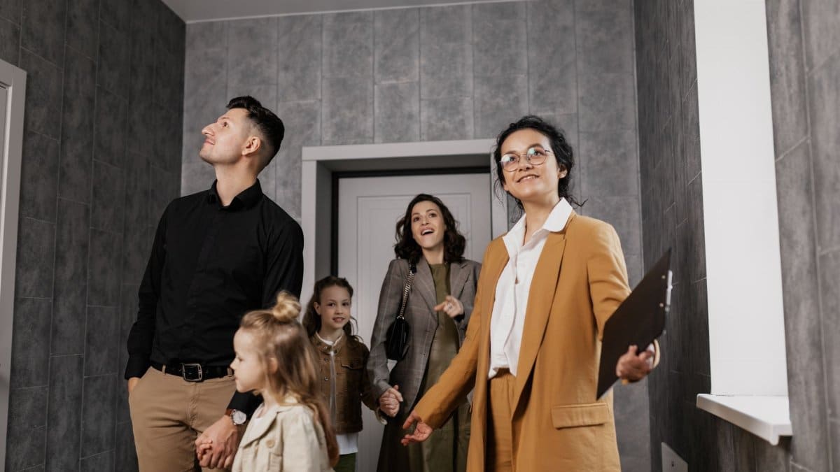 Happy family exploring a new home with a professional real estate agent guiding the tour.