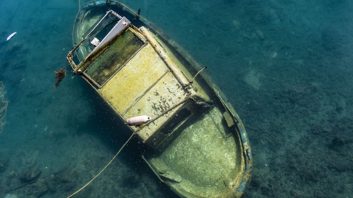 From above of old shabby abandoned boat sunken in sea water on sunny day