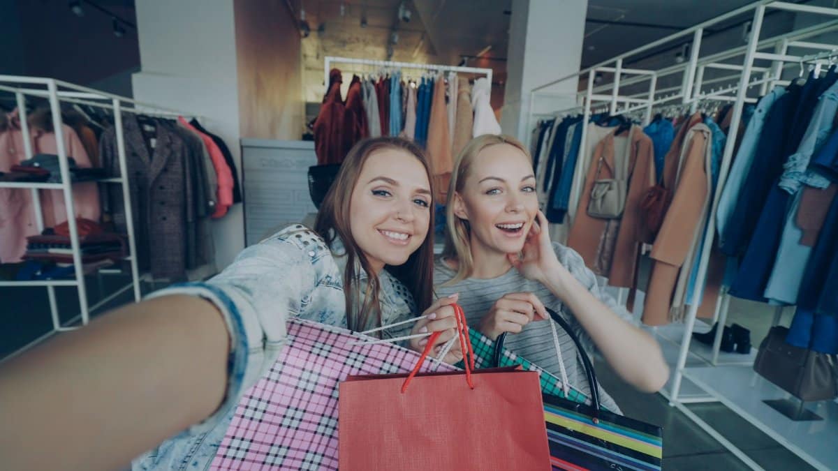 Two women happily shopping with bags in a fashionable clothing store.