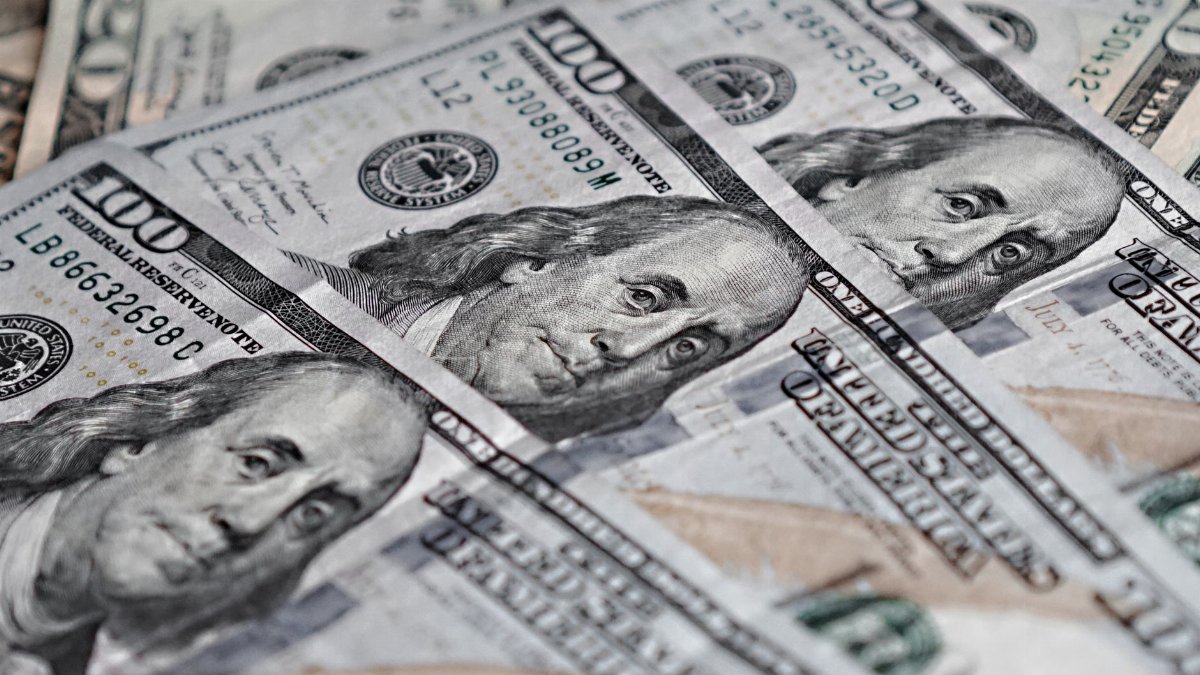 Close-up view of several US hundred dollar bills with Benjamin Franklin's portrait.