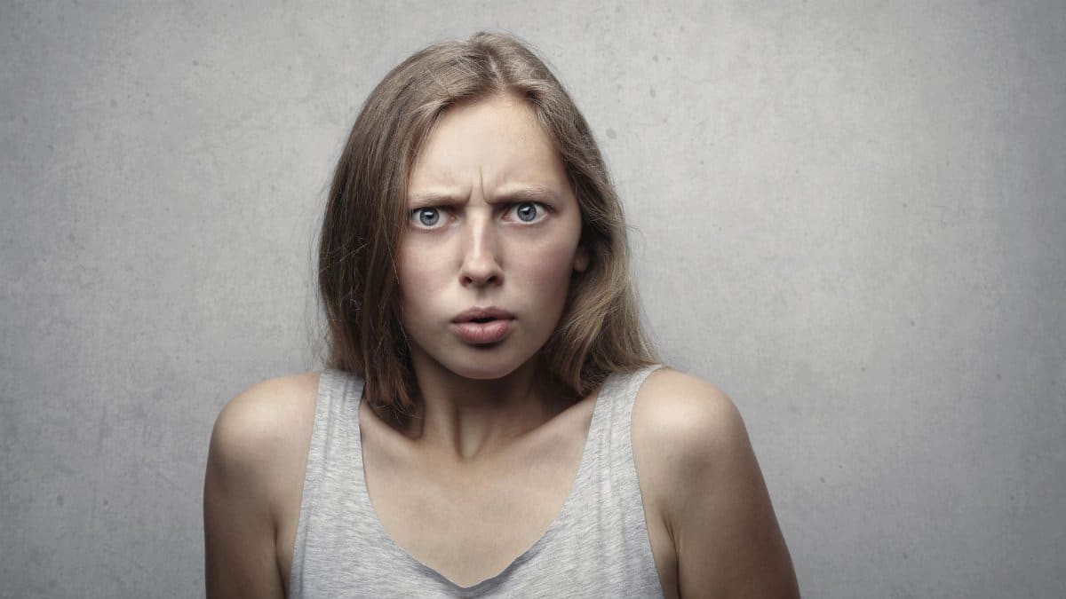 Close-up portrait of a pensive woman with a confused facial expression indoors.