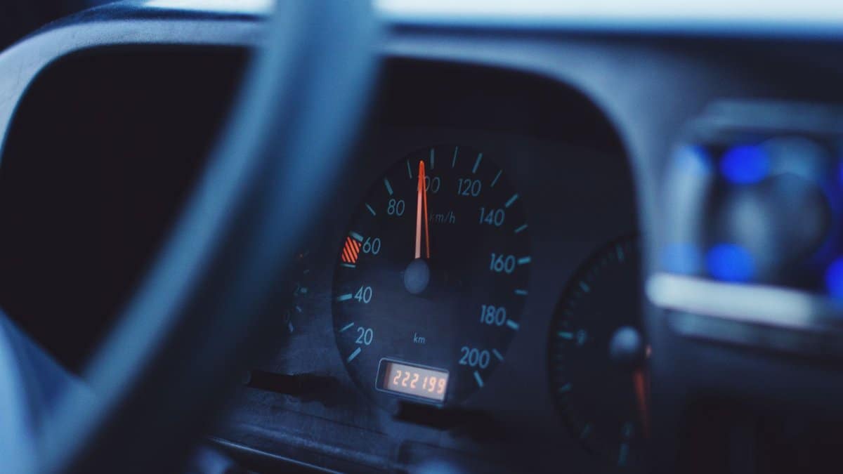 Focused image of a car's speedometer and tachometer under dim lighting, showing mileage and speed.