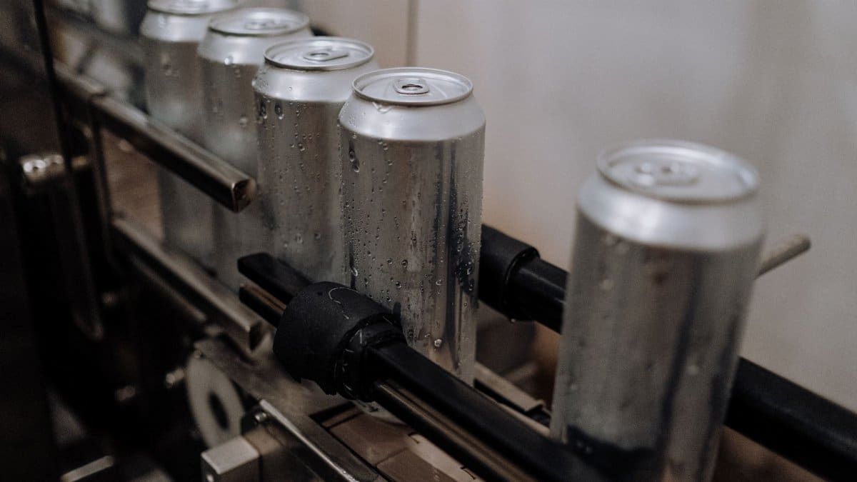 Close-up of aluminum cans with water droplets on a production line, showcasing industrial beverage processing.