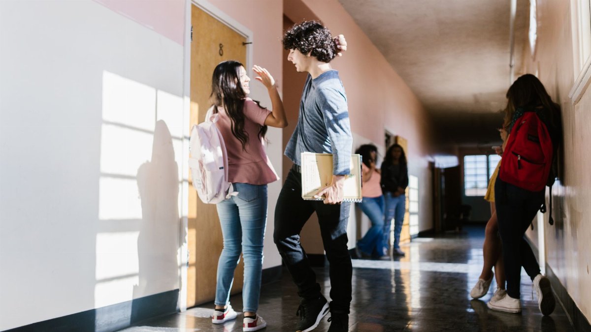High school students casually interact in a brightly lit hallway.
