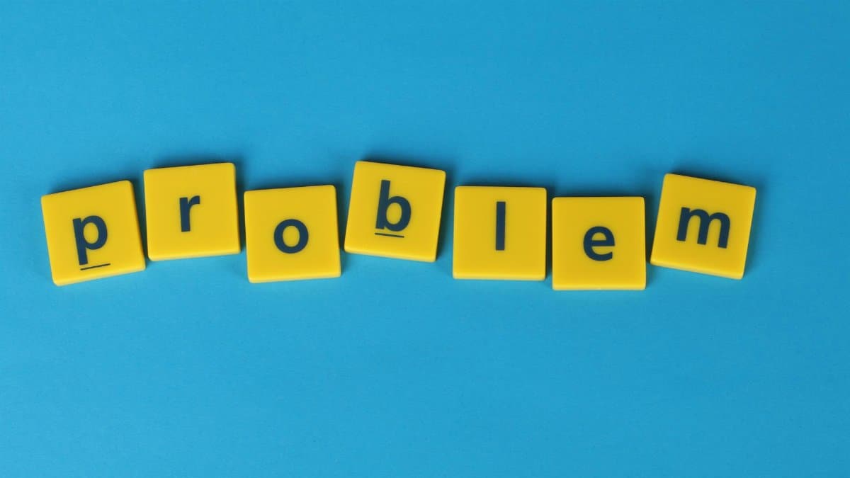 Yellow Scrabble tiles spelling 'problem' on a blue background, symbolizing challenge.