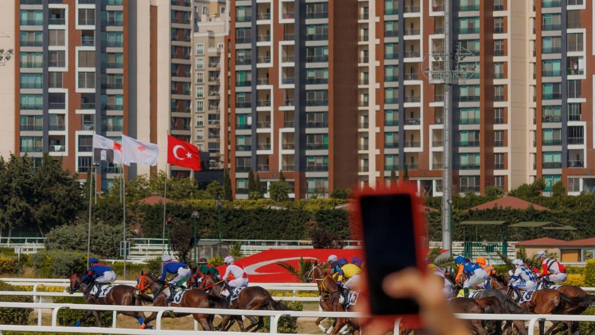 Exciting horse race captured with skyscrapers and Turkish flag in the background. Motion and urban vibes.