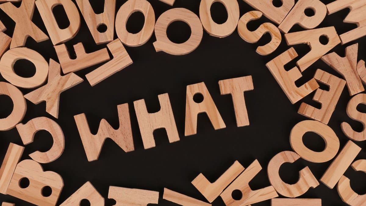 Artistic arrangement of wooden letters spelling 'WHAT' on a black background, offering creative inspiration.