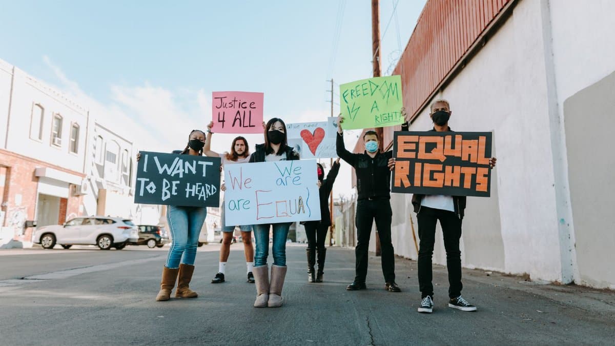 A group of people holding signs for equality and justice during an outdoor protest for human rights.