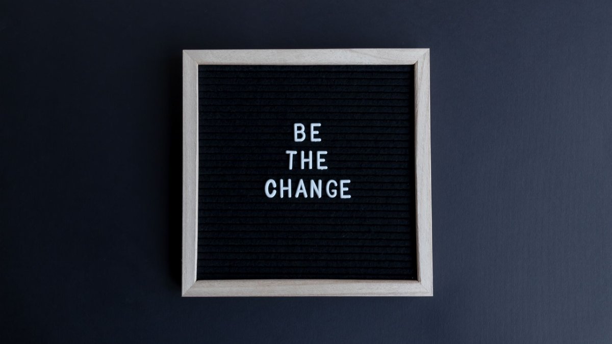 A simple letter board with the motivational message 'Be the Change' on a dark background.