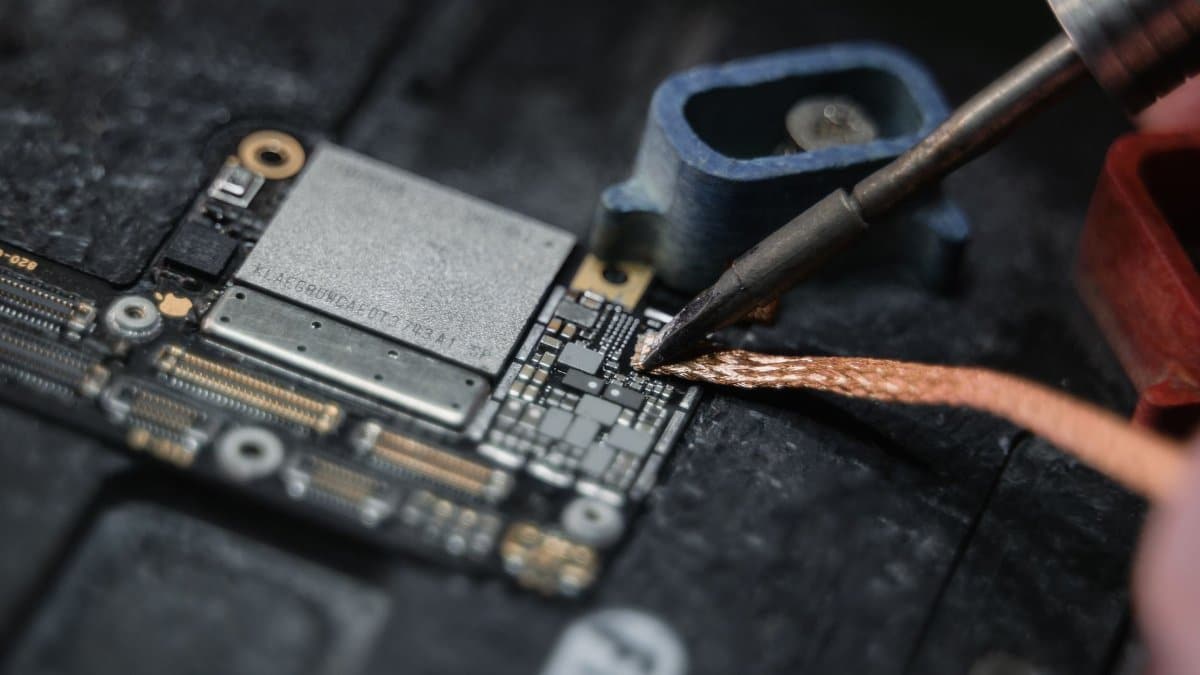 Detailed close-up of a soldering iron working on a circuit board, showcasing electronics repair.