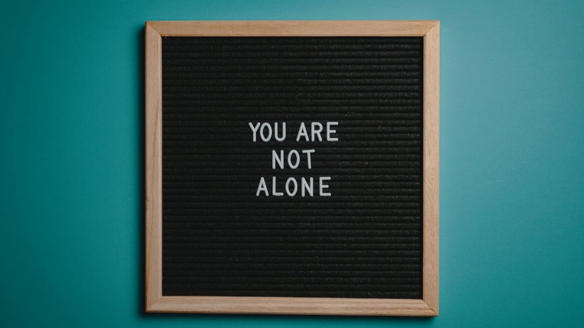 A wooden letter board displays a motivational message against a teal background.