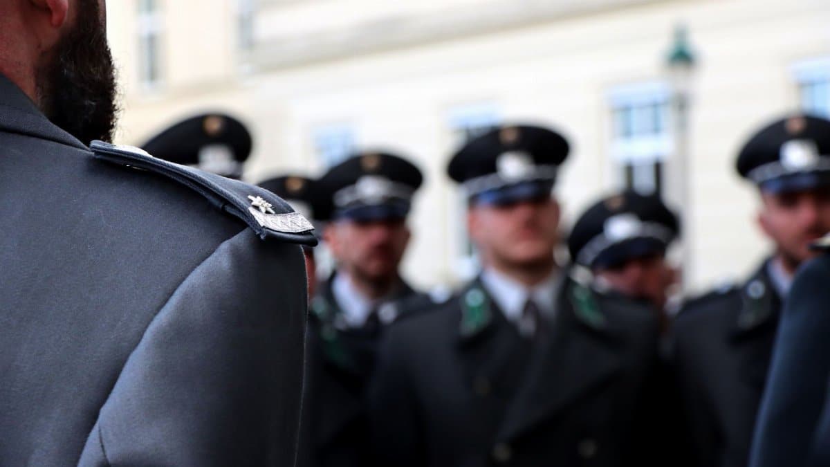 Blurred group of uniformed officers in formation, focusing on insignia and uniform details.