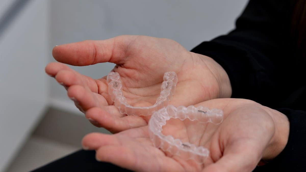 Hands holding clear dental aligners in a modern dental office in Belo Horizonte.