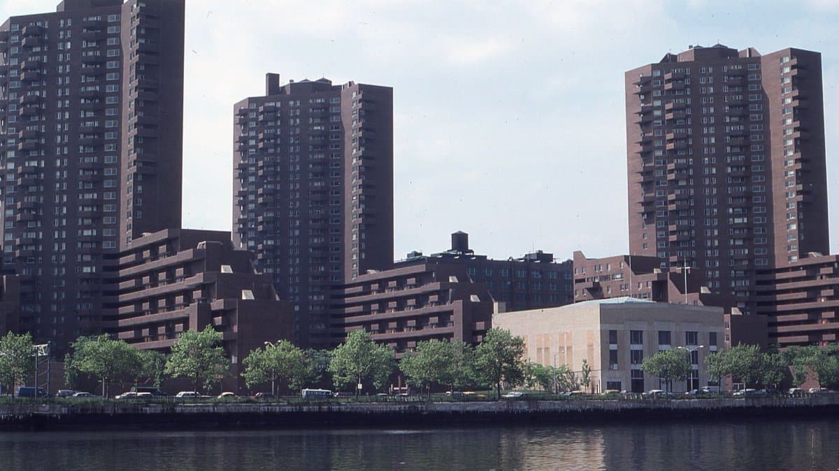 Cityscape of urban skyline with modern buildings by the waterfront under clouded sky.