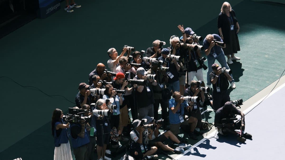 A large group of photographers with cameras and lenses taking photos at an outdoor event.