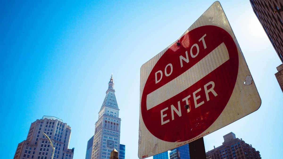 Street view of a Do Not Enter sign against the iconic New York City skyline.