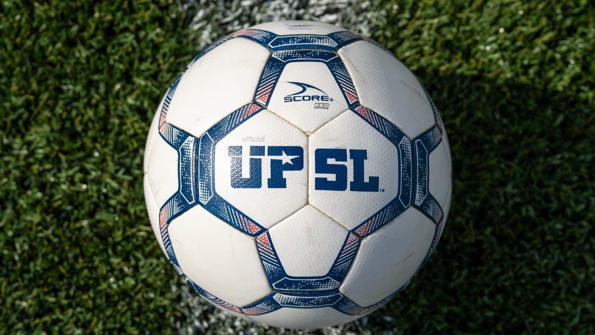 Official UPSL soccer ball resting on green artificial turf field, showcasing sports equipment.