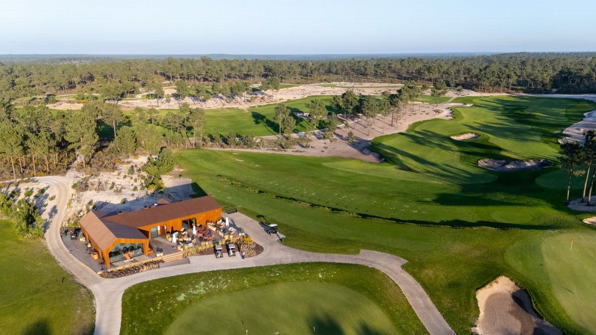 Aerial shot of a golf course with clubhouse in Setúbal, Portugal, surrounded by lush greenery.