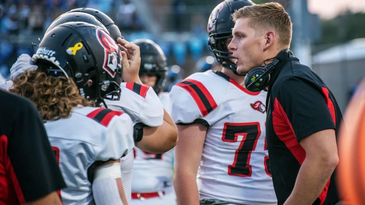 Football coach motivating players on field during a game in Idaho Falls.