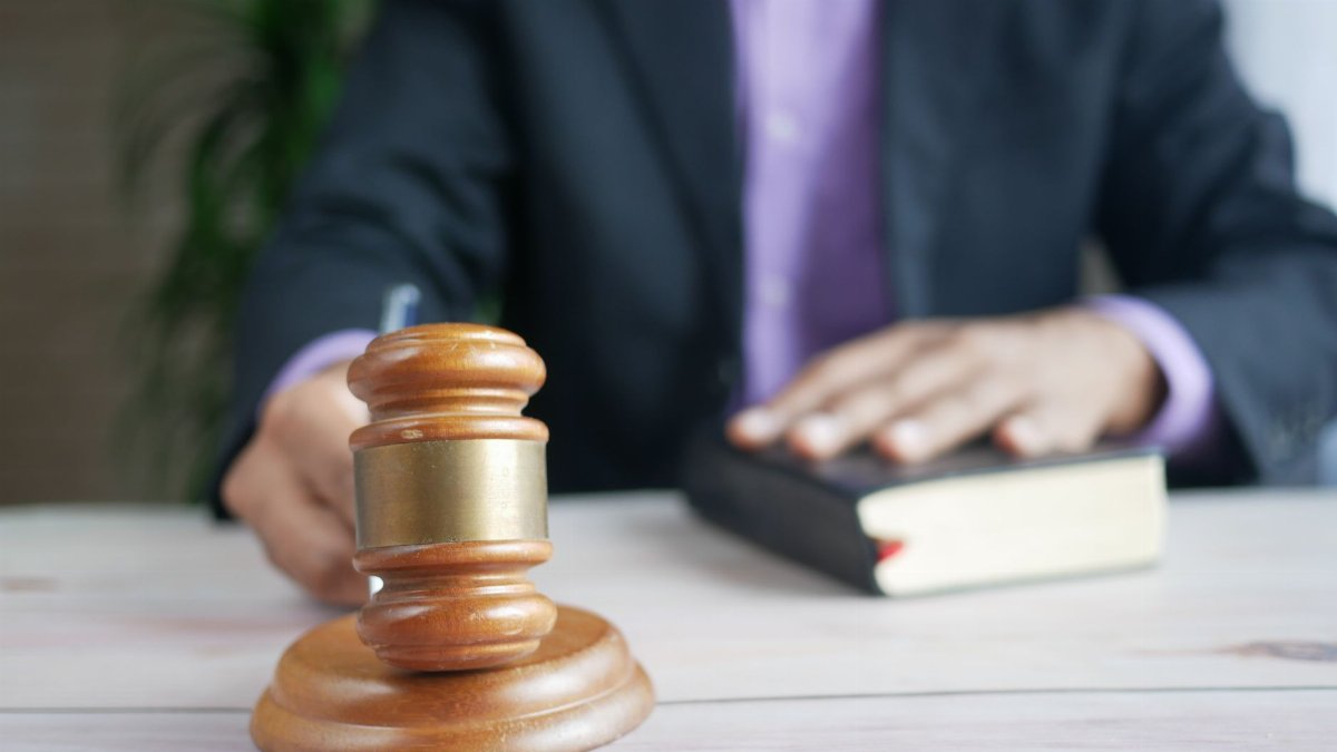 A wooden gavel and legal book represent justice in a court setting, emphasizing order and legal authority.